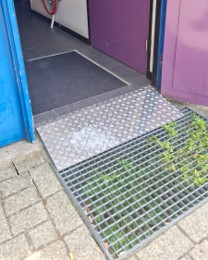 Foto van een relatief smalle deuropening met een kleine drempel en korte helling.